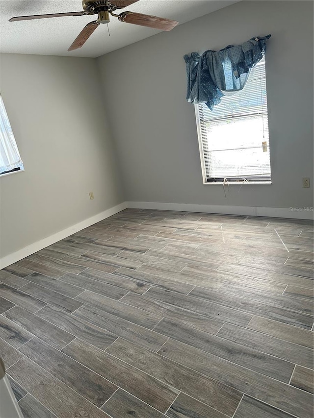 empty room with dark wood-type flooring, a textured ceiling, and ceiling fan