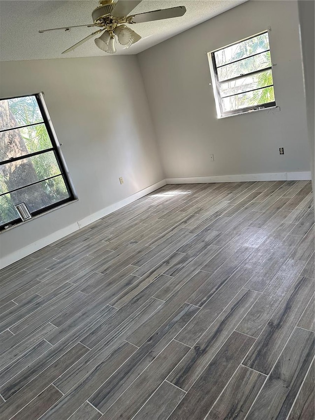 unfurnished room with dark hardwood / wood-style floors, a textured ceiling, and plenty of natural light