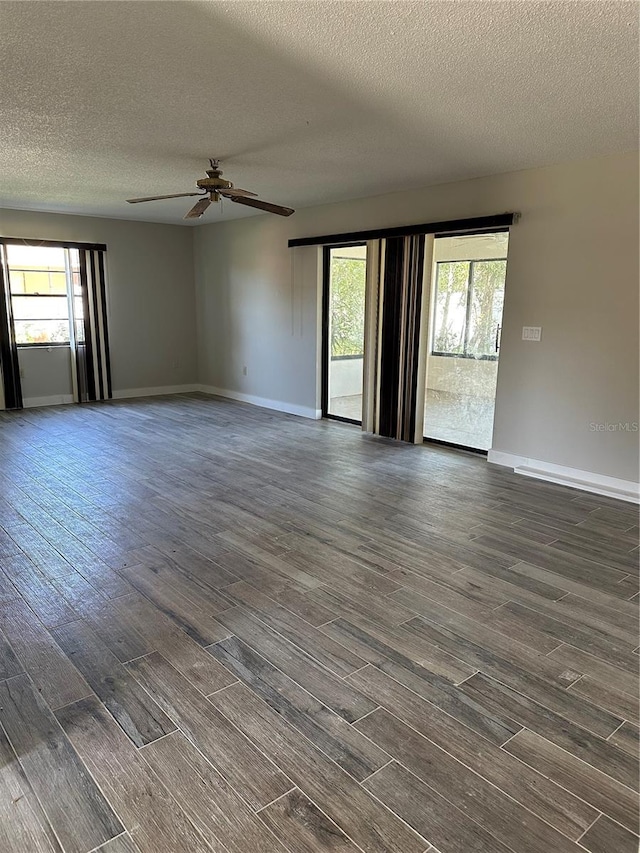 spare room featuring a textured ceiling, dark wood-type flooring, and plenty of natural light