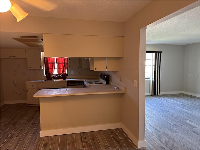 kitchen featuring kitchen peninsula, ceiling fan, a textured ceiling, dark hardwood / wood-style floors, and white range with gas stovetop