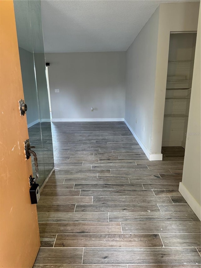 spare room featuring a textured ceiling and dark hardwood / wood-style flooring