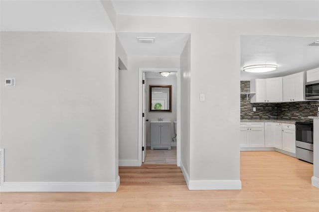 kitchen featuring appliances with stainless steel finishes, light hardwood / wood-style flooring, and white cabinets