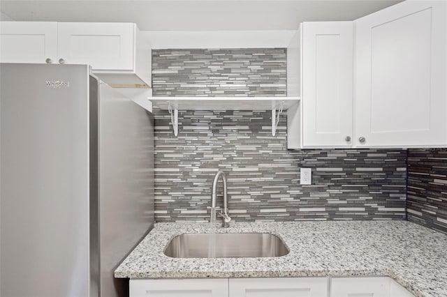 kitchen with stainless steel fridge, white cabinets, and sink