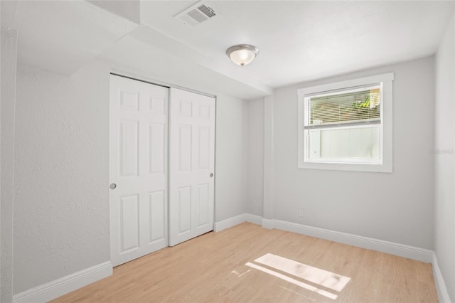 unfurnished bedroom with a closet and light wood-type flooring