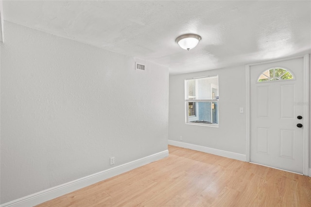 foyer entrance featuring light hardwood / wood-style flooring, a textured ceiling, and plenty of natural light