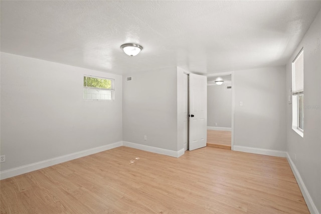 empty room with light hardwood / wood-style flooring and a textured ceiling