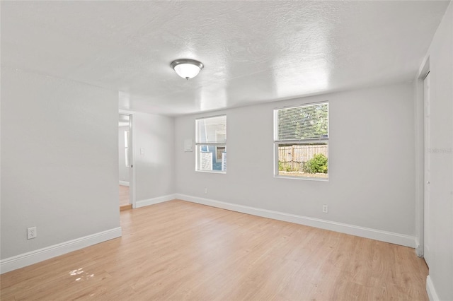 unfurnished room featuring light hardwood / wood-style flooring and a textured ceiling