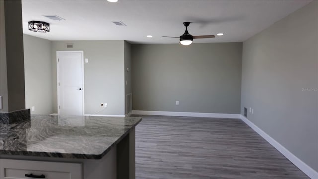 kitchen with dark wood-type flooring, white cabinetry, dark stone counters, and ceiling fan