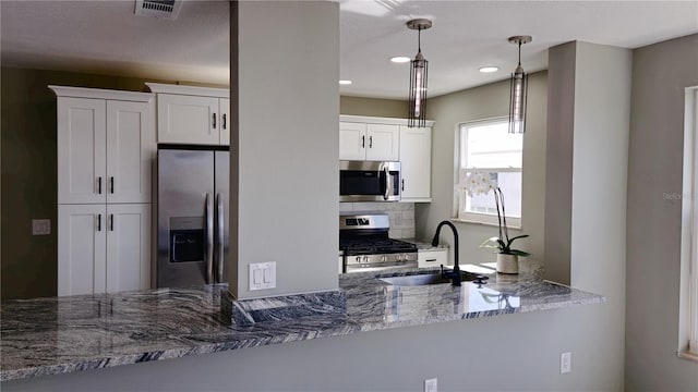 kitchen featuring hanging light fixtures, sink, white cabinetry, stone counters, and appliances with stainless steel finishes