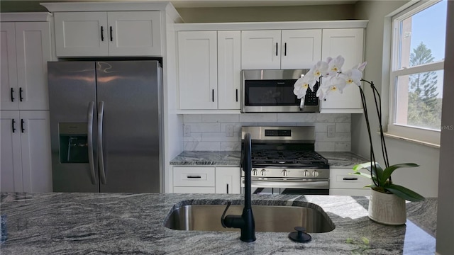 kitchen featuring a wealth of natural light, decorative backsplash, white cabinetry, and stainless steel appliances