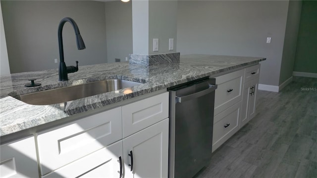 5623 80th St N Unit 510, Saint Petersburg, FL 33709 - kitchen featuring stainless steel dishwasher, a sink, white cabinetry, light stone counters, and light wood-style floors