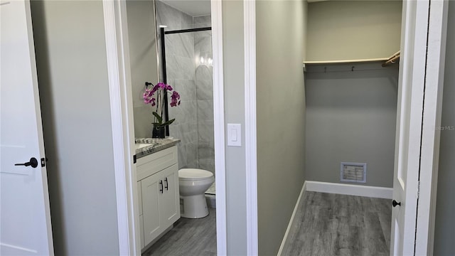 bathroom with a shower with door, vanity, hardwood / wood-style floors, and toilet