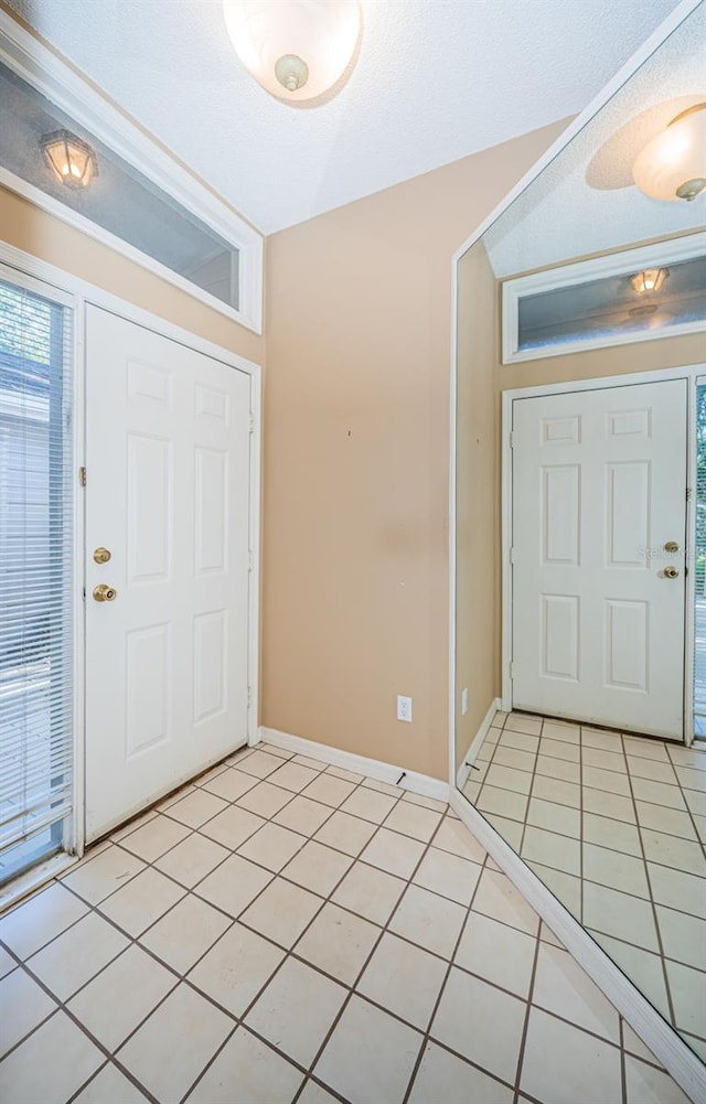 foyer entrance with a textured ceiling and light tile patterned floors