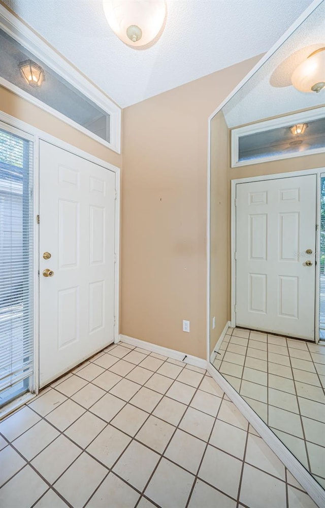 foyer with light tile patterned floors, baseboards, and plenty of natural light