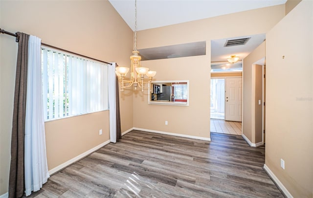 unfurnished room with a notable chandelier, dark hardwood / wood-style floors, and vaulted ceiling