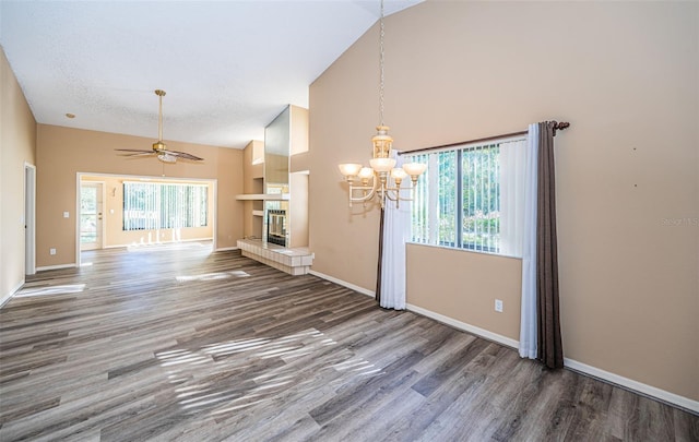 unfurnished living room with a textured ceiling, ceiling fan with notable chandelier, a fireplace, and dark hardwood / wood-style flooring