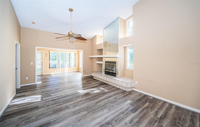 unfurnished living room with a wealth of natural light, a textured ceiling, high vaulted ceiling, and dark hardwood / wood-style flooring