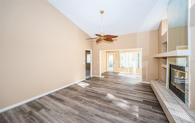 unfurnished living room with baseboards, a fireplace, wood finished floors, a ceiling fan, and high vaulted ceiling