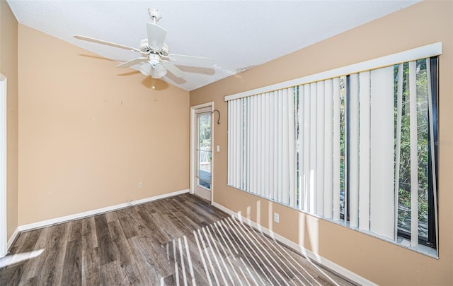 spare room with wood finished floors, a ceiling fan, and baseboards