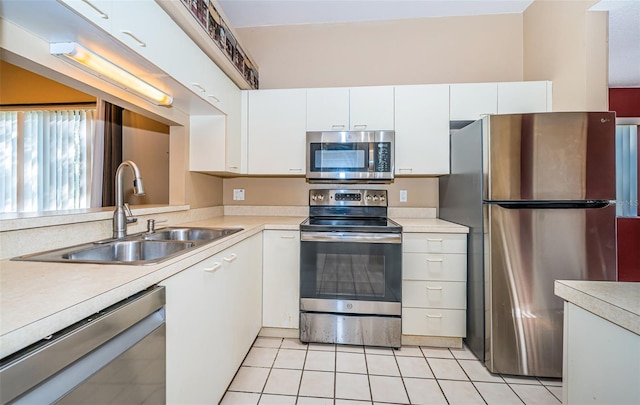 kitchen with appliances with stainless steel finishes, light countertops, white cabinets, a sink, and light tile patterned flooring