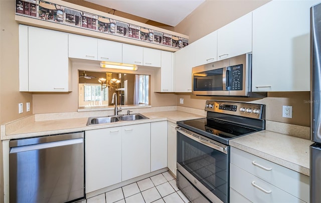 kitchen featuring appliances with stainless steel finishes, light tile patterned flooring, white cabinetry, and sink