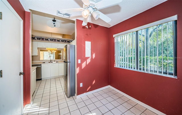 kitchen with sink, stainless steel fridge, white cabinetry, and plenty of natural light