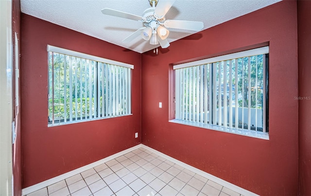 tiled spare room with a textured ceiling, ceiling fan, and baseboards