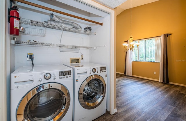 clothes washing area featuring a chandelier, washer and clothes dryer, laundry area, baseboards, and wood finished floors