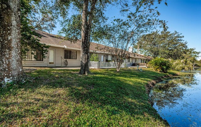 back of house with a water view and a yard
