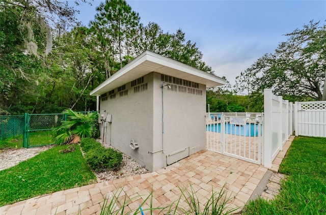 view of outdoor structure featuring a gate, a fenced backyard, an outbuilding, and a fenced in pool