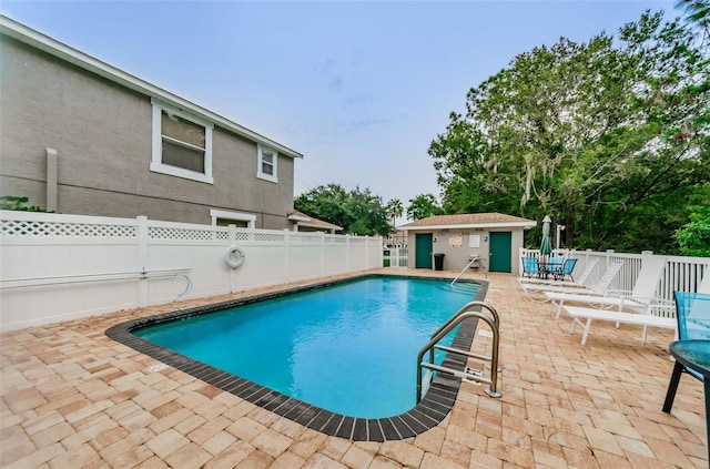 view of swimming pool featuring an outbuilding and a patio