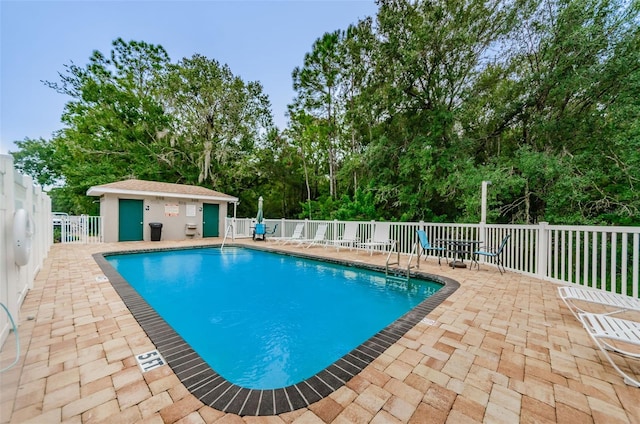 view of swimming pool featuring a patio and an outbuilding