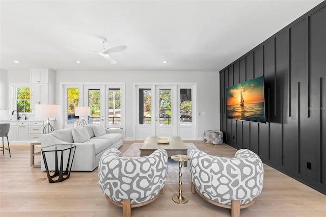 living room with sink, light hardwood / wood-style floors, and ceiling fan