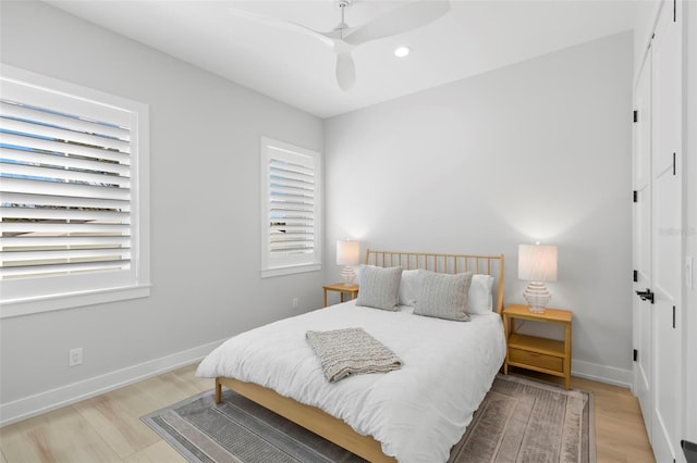 bedroom featuring ceiling fan, multiple windows, and light hardwood / wood-style floors