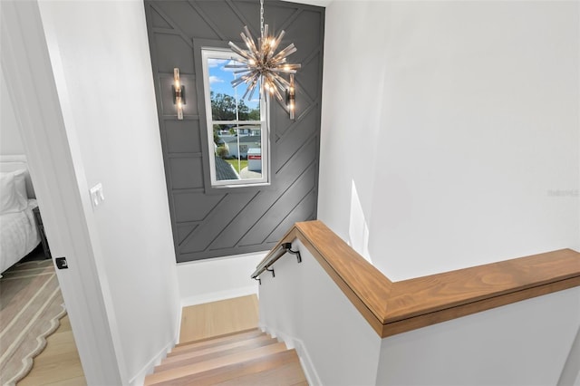 staircase with a notable chandelier and hardwood / wood-style flooring