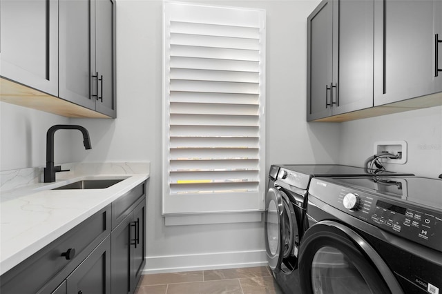 laundry area featuring tile patterned floors, cabinets, sink, and washing machine and clothes dryer