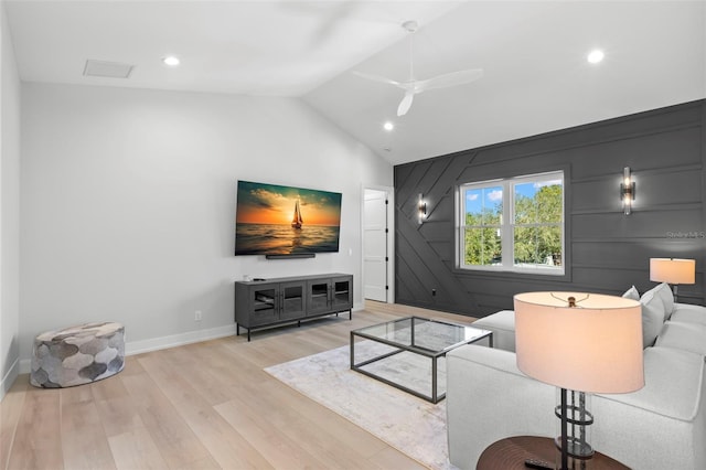 living room with wood walls, vaulted ceiling, light hardwood / wood-style flooring, and ceiling fan