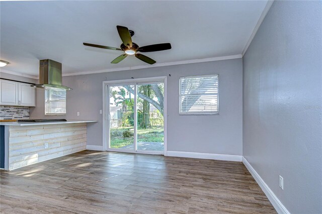 unfurnished living room featuring light hardwood / wood-style floors, ceiling fan, and ornamental molding