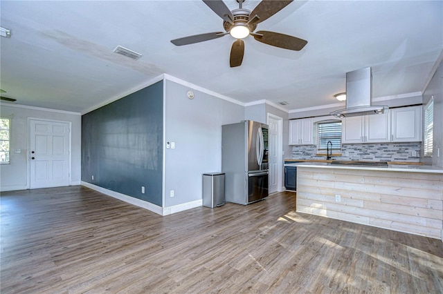 kitchen with backsplash, stainless steel fridge, light wood-type flooring, and ornamental molding