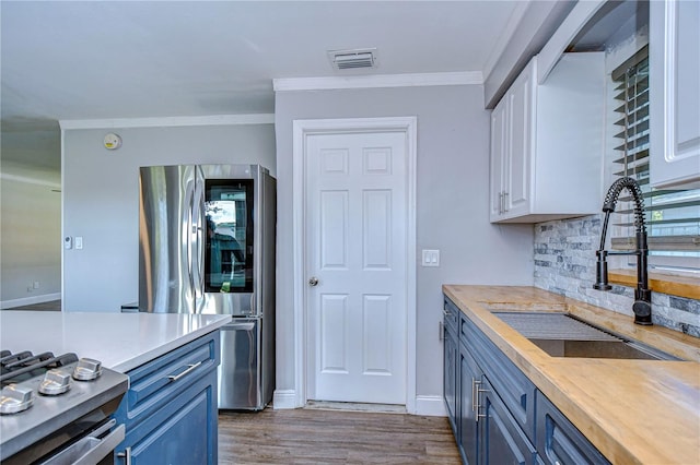 kitchen with butcher block counters, stainless steel fridge, white cabinetry, and light hardwood / wood-style flooring