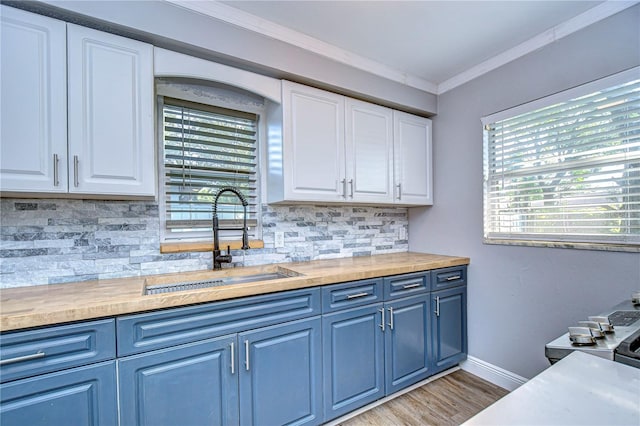 kitchen with crown molding, butcher block counters, white cabinetry, decorative backsplash, and sink