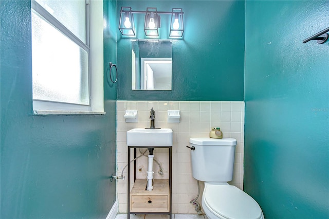 bathroom featuring sink, toilet, and tile walls