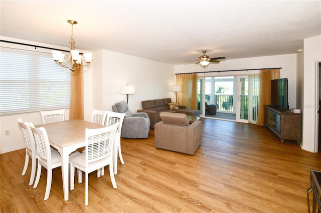 dining room with a textured ceiling, light wood-type flooring, and ceiling fan with notable chandelier