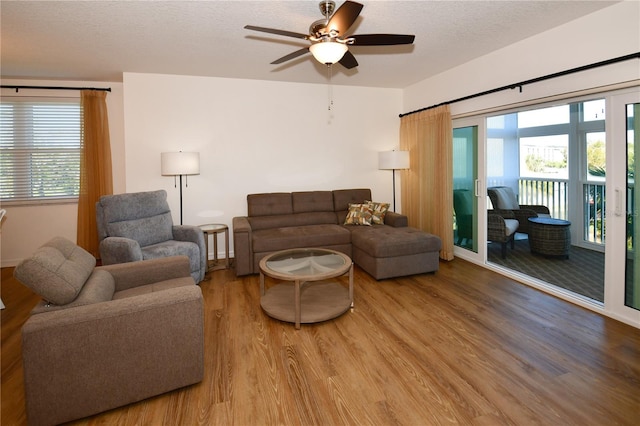 living room with hardwood / wood-style floors, a textured ceiling, and ceiling fan