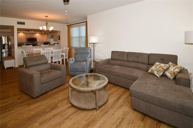 living room featuring a notable chandelier and light wood-type flooring