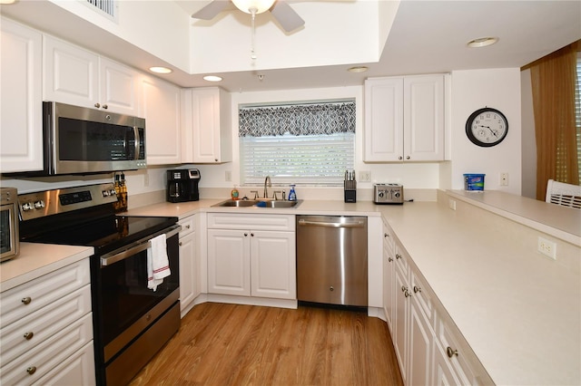 kitchen with ceiling fan, appliances with stainless steel finishes, white cabinetry, light hardwood / wood-style flooring, and sink