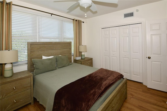 bedroom with a closet, dark wood-type flooring, and ceiling fan