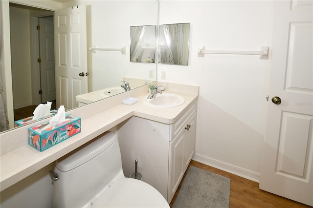 bathroom with toilet, vanity, and wood-type flooring