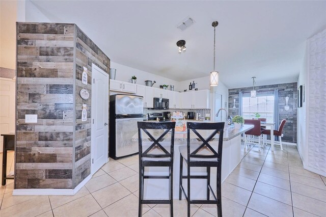 612 Chicago Way, Dundee, FL 33838 - kitchen featuring freestanding refrigerator, black microwave, white cabinetry, an island with sink, and light tile patterned floors