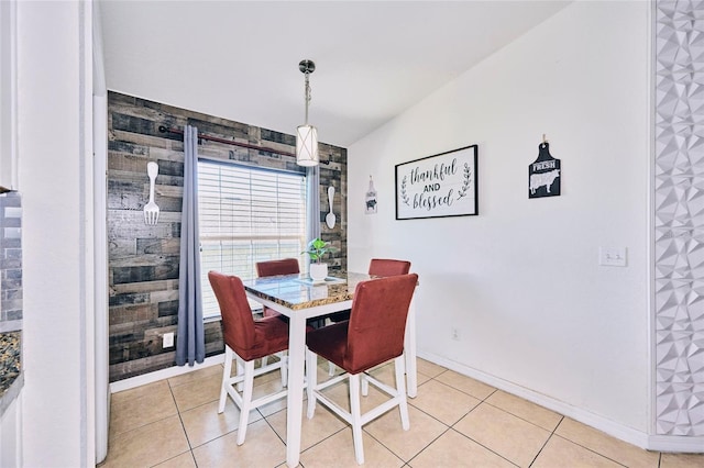 dining area with wooden walls, vaulted ceiling, and light tile patterned flooring